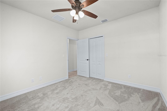 unfurnished bedroom with a closet, light colored carpet, and ceiling fan