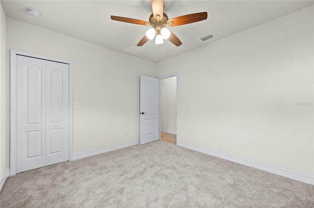 unfurnished bedroom with a closet, light colored carpet, and ceiling fan