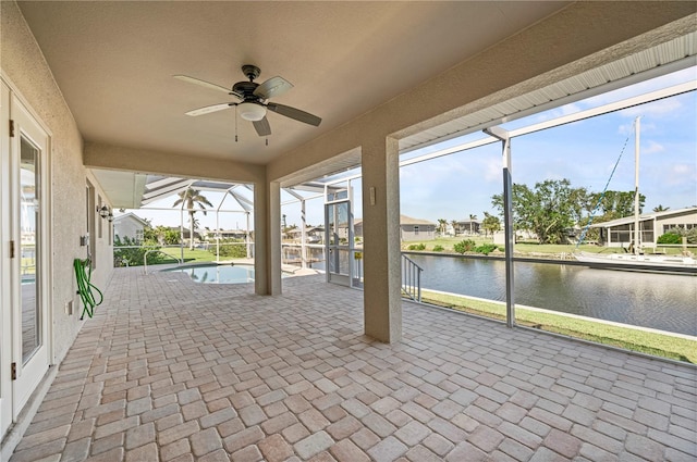 view of patio with ceiling fan, a water view, and glass enclosure