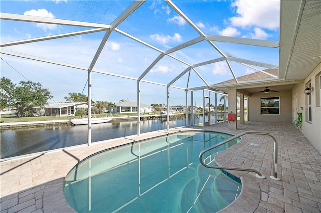 view of pool with glass enclosure, a patio area, and a water view