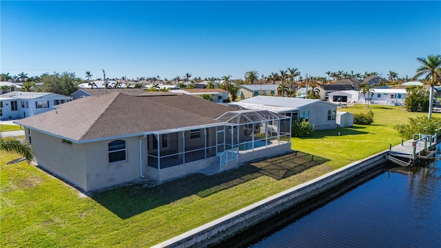 back of property featuring a yard, a water view, and glass enclosure