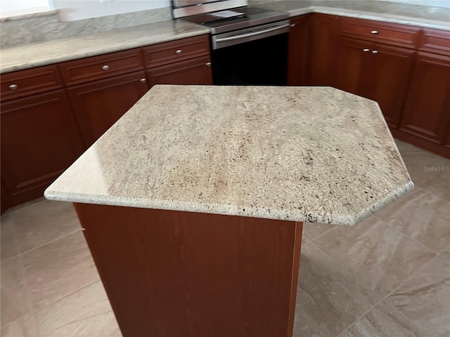 kitchen with a kitchen island, light stone counters, and electric stove