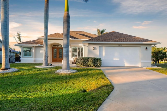 single story home with a yard, french doors, and a garage