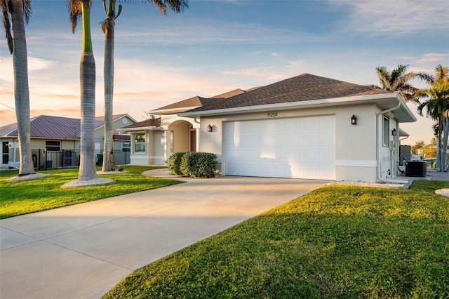 ranch-style home featuring a garage, a yard, and central AC