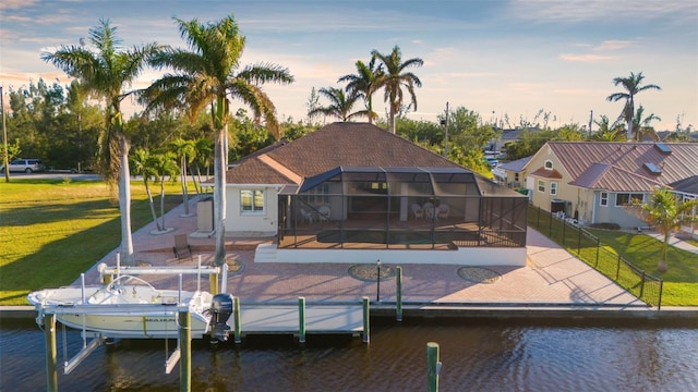 dock area with a lanai, a patio area, a water view, and a lawn