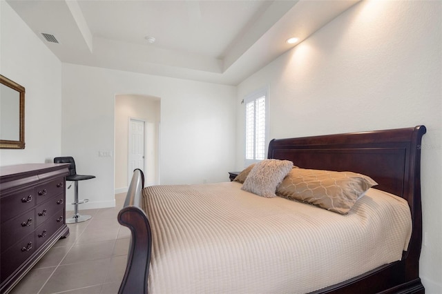 bedroom with tile patterned flooring and a raised ceiling