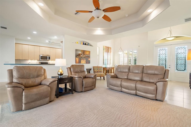 tiled living room with french doors, a raised ceiling, and ceiling fan