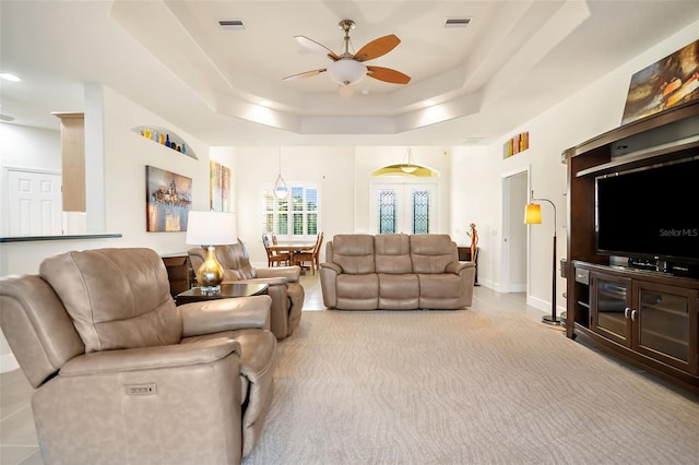 carpeted living room featuring french doors, a tray ceiling, and ceiling fan