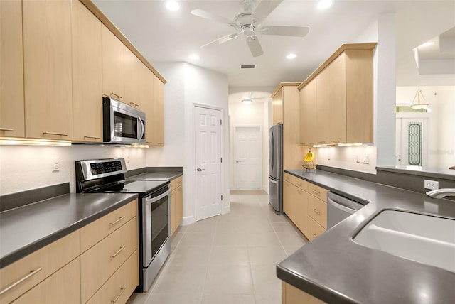 kitchen with sink, light brown cabinetry, light tile patterned floors, and appliances with stainless steel finishes