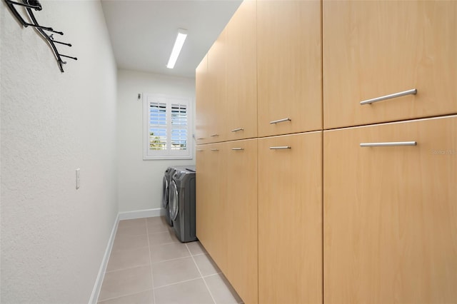 washroom featuring washer and clothes dryer, cabinets, and light tile patterned floors