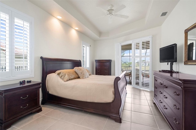 tiled bedroom featuring access to outside, a raised ceiling, multiple windows, and ceiling fan