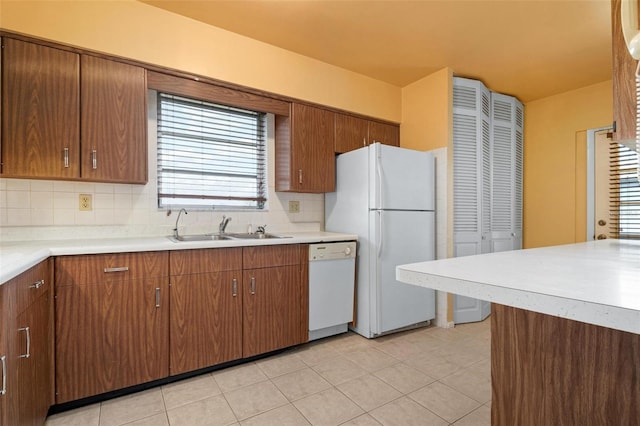 kitchen featuring tasteful backsplash, sink, light tile patterned floors, and white appliances