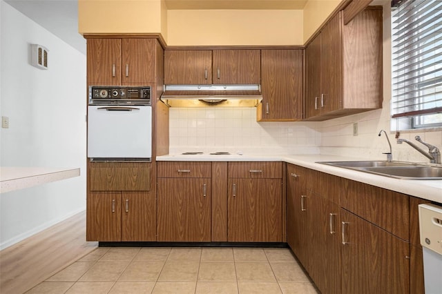 kitchen featuring tasteful backsplash, sink, light tile patterned flooring, and white appliances