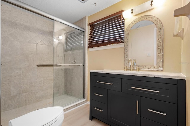 bathroom featuring vanity, a shower with shower door, a textured ceiling, and toilet