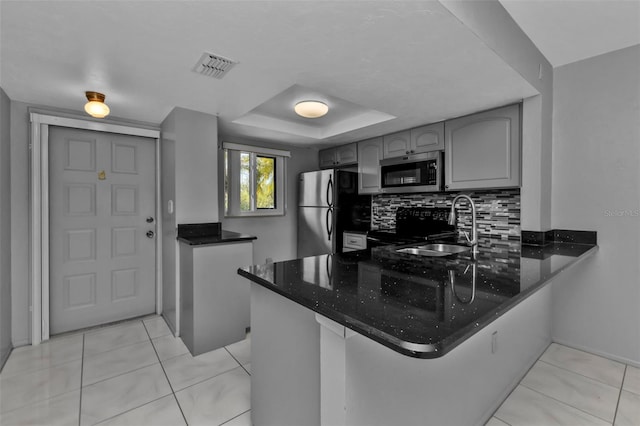 kitchen with gray cabinetry, kitchen peninsula, backsplash, and appliances with stainless steel finishes