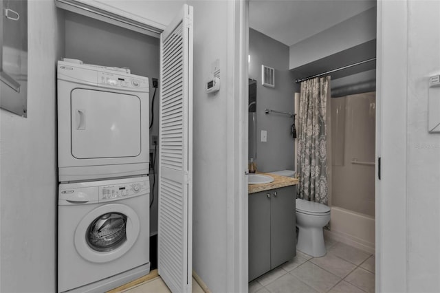 laundry area with light tile patterned floors, stacked washer and clothes dryer, and sink