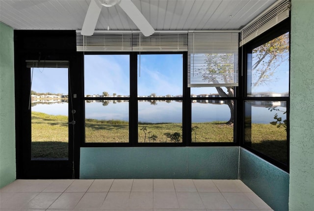 unfurnished sunroom featuring ceiling fan and a water view