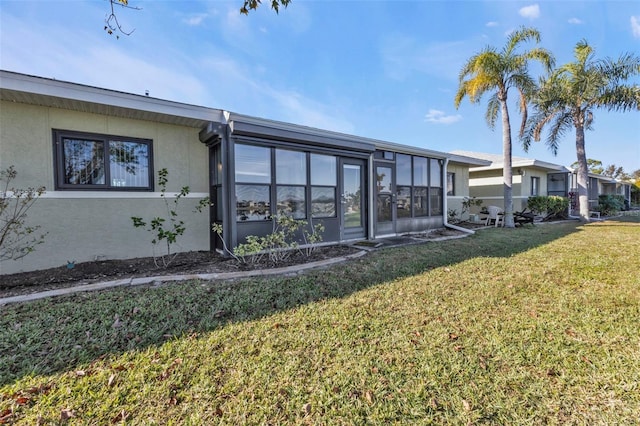 rear view of property featuring a sunroom and a yard