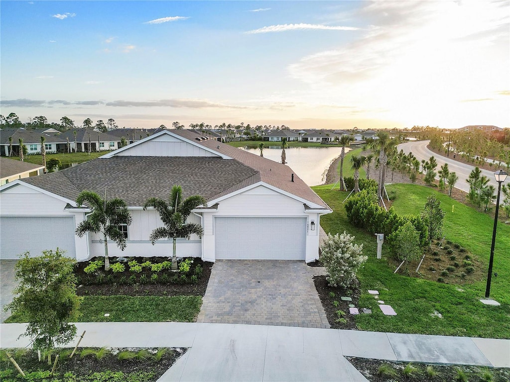 view of front of home featuring a garage, a residential view, a front lawn, and decorative driveway