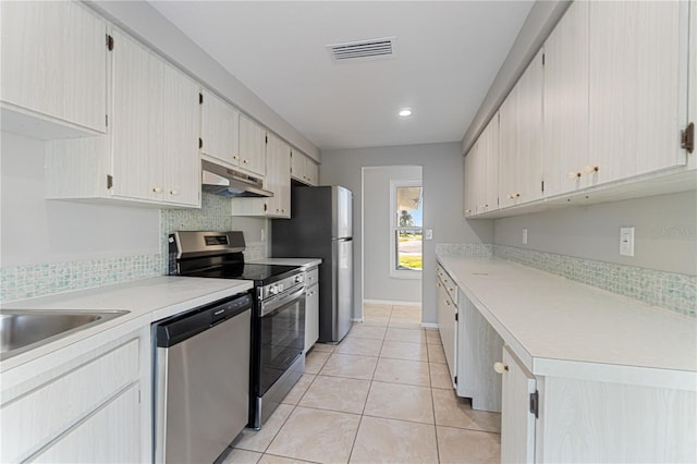 kitchen with appliances with stainless steel finishes, sink, tasteful backsplash, and light tile patterned flooring