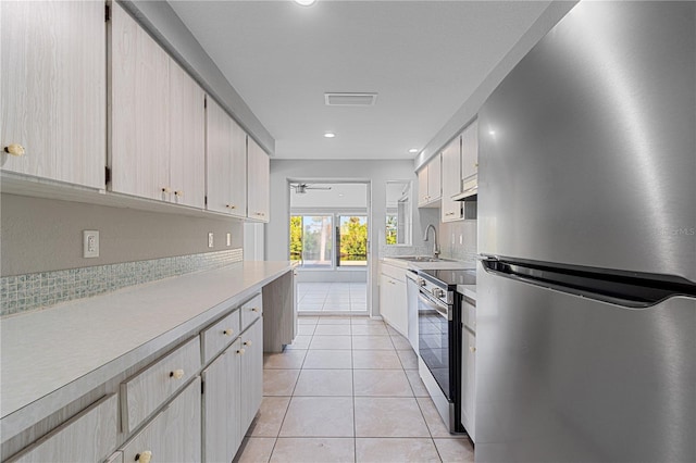 kitchen featuring appliances with stainless steel finishes, light tile patterned floors, ceiling fan, and sink