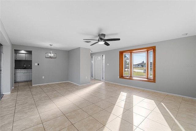 unfurnished room with sink, light tile patterned flooring, and ceiling fan with notable chandelier