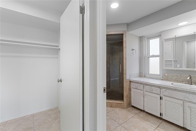 bathroom with tile patterned flooring, vanity, and walk in shower