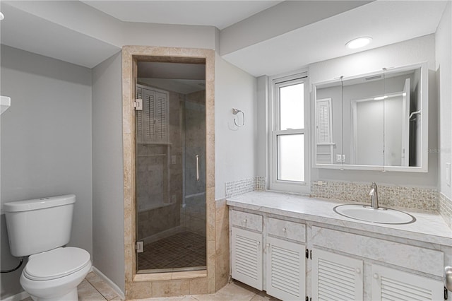 bathroom featuring tile patterned floors, vanity, toilet, and a shower with door