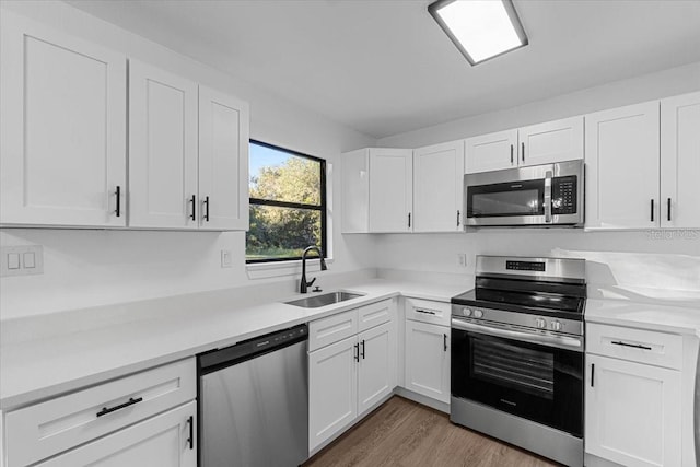 kitchen with white cabinets, sink, wood-type flooring, and stainless steel appliances