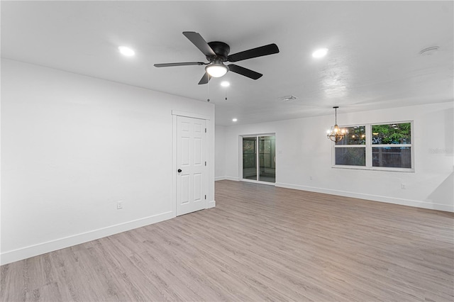 empty room featuring ceiling fan with notable chandelier and light hardwood / wood-style flooring