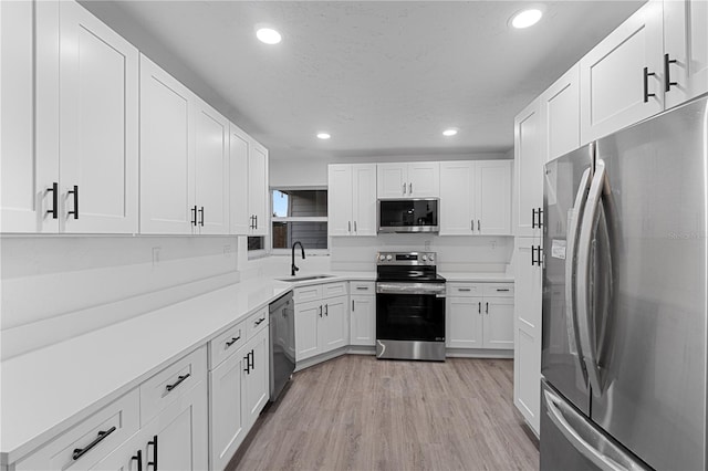 kitchen featuring sink, white cabinets, light wood-type flooring, and appliances with stainless steel finishes