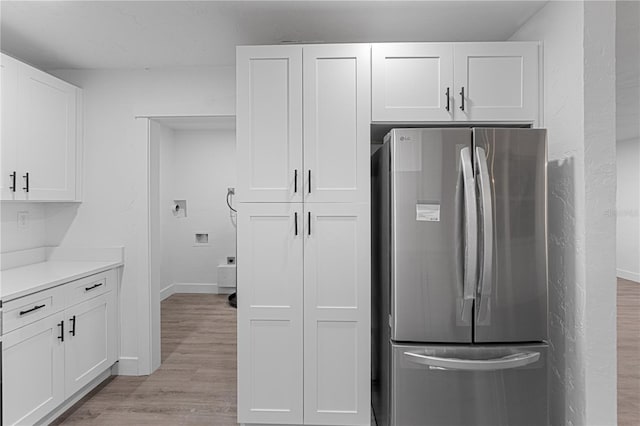 kitchen featuring white cabinets, stainless steel fridge, and light hardwood / wood-style flooring