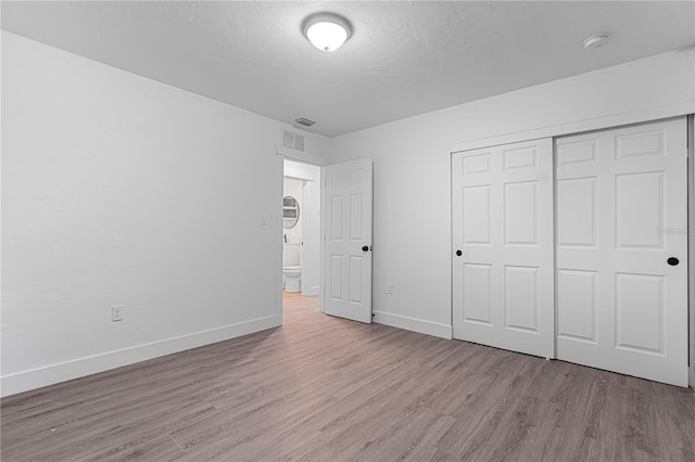 unfurnished bedroom with light hardwood / wood-style flooring and a closet