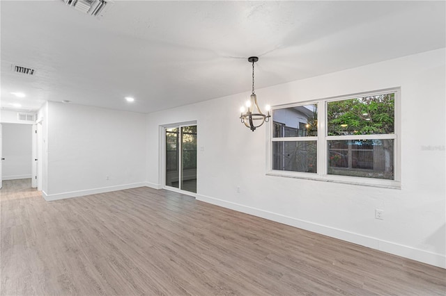 spare room with hardwood / wood-style floors and a notable chandelier