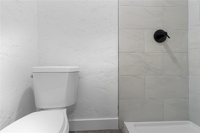 bathroom featuring hardwood / wood-style floors, toilet, and a tile shower