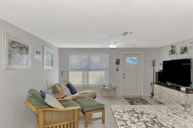 tiled living room featuring ceiling fan and a textured ceiling