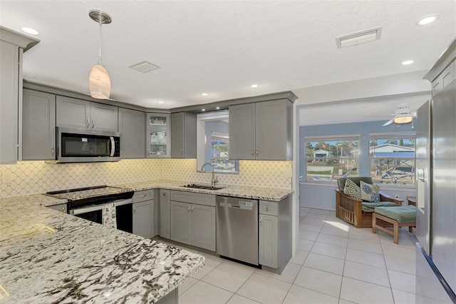 kitchen featuring decorative light fixtures, gray cabinets, light stone countertops, and stainless steel appliances