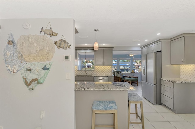 kitchen with decorative backsplash, a kitchen bar, stainless steel appliances, and gray cabinets