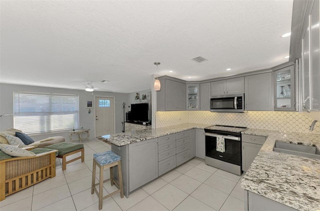 kitchen with gray cabinetry, sink, pendant lighting, decorative backsplash, and appliances with stainless steel finishes