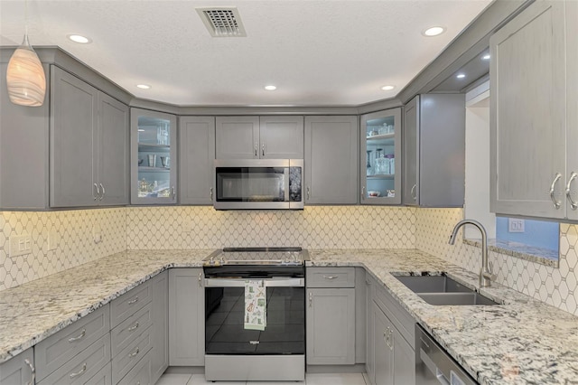 kitchen featuring light stone countertops, decorative light fixtures, stainless steel appliances, and sink