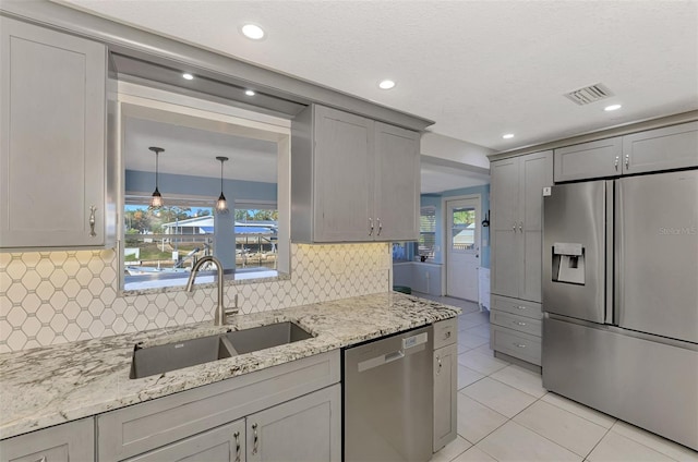 824 E 6th St, Englewood, FL 34223 - kitchen with appliances with stainless steel finishes, light tile patterned floors, light stone countertops, gray cabinets, and decorative backsplash