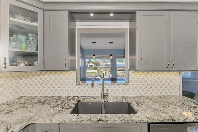 824 E 6th St, Englewood, FL 34223 - kitchen with glass insert cabinets, gray cabinetry, light stone counters, and tasteful backsplash