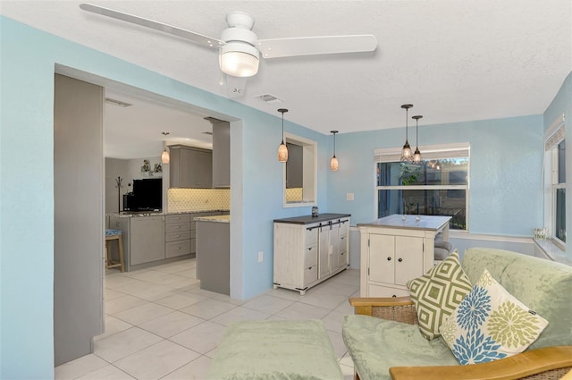 kitchen with backsplash, gray cabinetry, ceiling fan, light tile patterned floors, and a center island