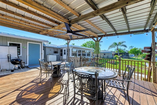 wooden terrace with a lawn, a sunroom, and ceiling fan