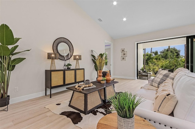 living room featuring high vaulted ceiling and light hardwood / wood-style flooring