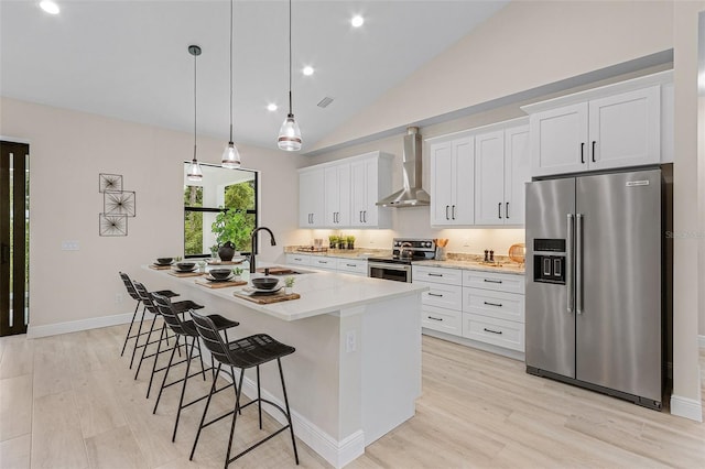 kitchen with white cabinetry, sink, wall chimney exhaust hood, stainless steel appliances, and an island with sink