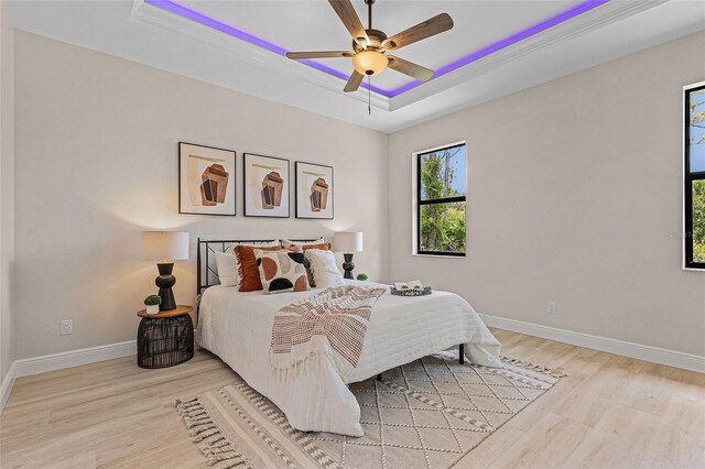 bedroom featuring light hardwood / wood-style floors, ceiling fan, and a tray ceiling