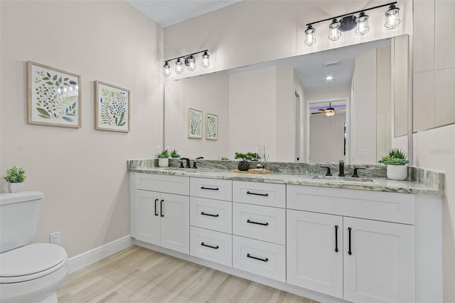 bathroom with wood-type flooring, vanity, toilet, and ceiling fan