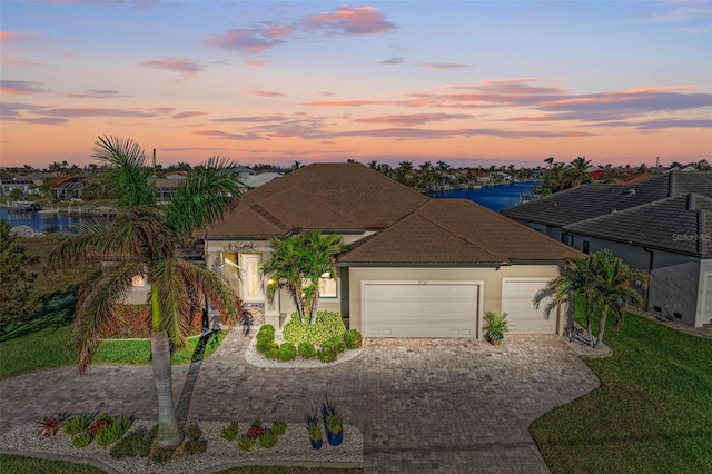 view of front facade with a yard, a water view, and a garage