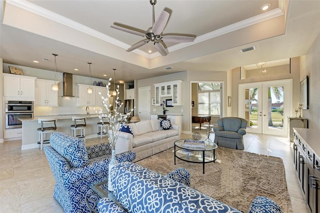 living room featuring a raised ceiling, ceiling fan, french doors, and ornamental molding